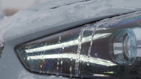 Moscow, Russia - CIRCA 2020: New car model Genesis G70 gray-blue on the road. Extreme close up of headlight with ice on it
