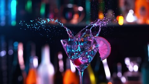 Camera Follows Ice cubes Falling into Glass of Fresh Fruit Cocktail in Bar. Super Slow Motion filmed on High Speed Cinema Camera.