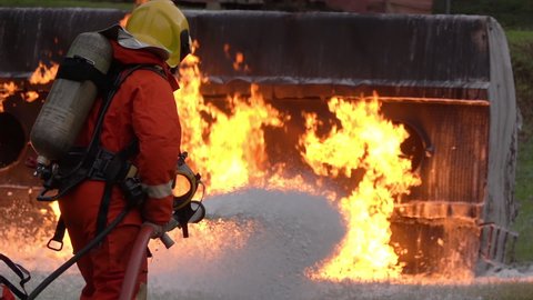 Slow motion: Firefighter using Chemical foam fire extinguisher to fighting with the fire flame from oil tanker truck accident. Firefighter safety disaster accident and public service concept.