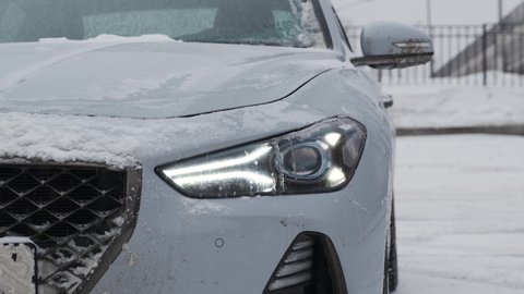 Moscow, Russia - CIRCA 2020: New car model Genesis G70 gray-blue on the road. Front headlight close up.