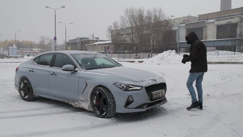 Moscow, Russia - CIRCA 2020: New car model Genesis G70 gray-blue on the road. professional photographer takes a photo of sedan model in winter