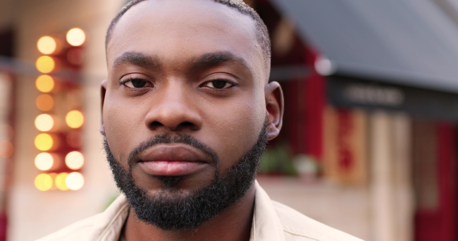 Portrait of serious African American young handsome man looking at camera and standing at street near cafe. Close up of good-looking male outdoor. Person in town outside. | Shutterstock HD Video #1065886192