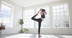 Beautiful Asian woman in sportswear is practicing yoga at home.