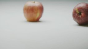 Apple bounce, organic red whole fruits moving on surface and roll off screen, close up studio video