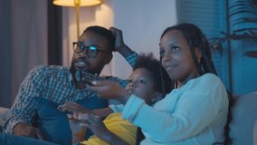 Cheerful afro-american family with kid resting on couch talking and watching tv in evening. Smiling african mom, dad and preteen son chatting and switching channels on tv with remote control - Powered by Shutterstock - Get 15% off with code: PIKWIZARD15