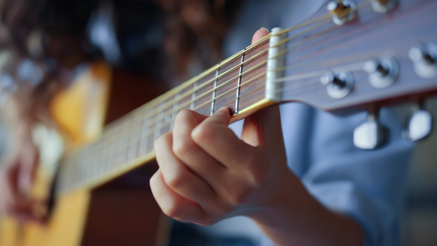 Girl hands playing acoustic guitar. Female musician creating music with string instrument. Unrecognizable woman recording guitar sound on smartphone. Guitarist fingers strumming strings on guitar