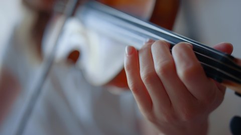 Closeup teenage girl hand playing violin. Unrecognizable woman fingers pressing strings on violin during performance. Female musician playing chords on string instrument