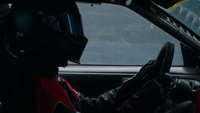 CU View of unrecognizable driver in protective wear driving a sports car, racing on a speedway. Shot with 2x anamorphic lens Royalty-Free Stock Footage #1065923542