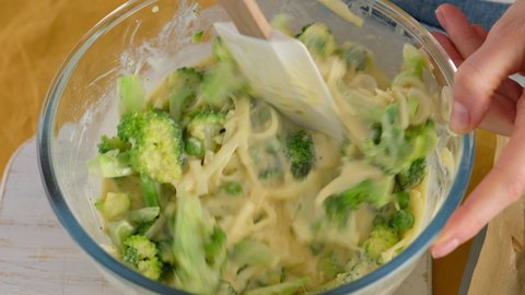 Close-up. Stir the ingredients in a glass bowl to make broccoli and cheese frittat in a baking dish. Italian breakfast. Baked chopped omelet with vegetables and broccoli. Healthy breakfast.