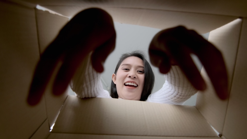 Asian woman excited happy opening unpacking a package parcel with surprised face reaction, shopping purchase from ecommerce online retail store, unpack delivered cardboard box taking out product. | Shutterstock HD Video #1065924205