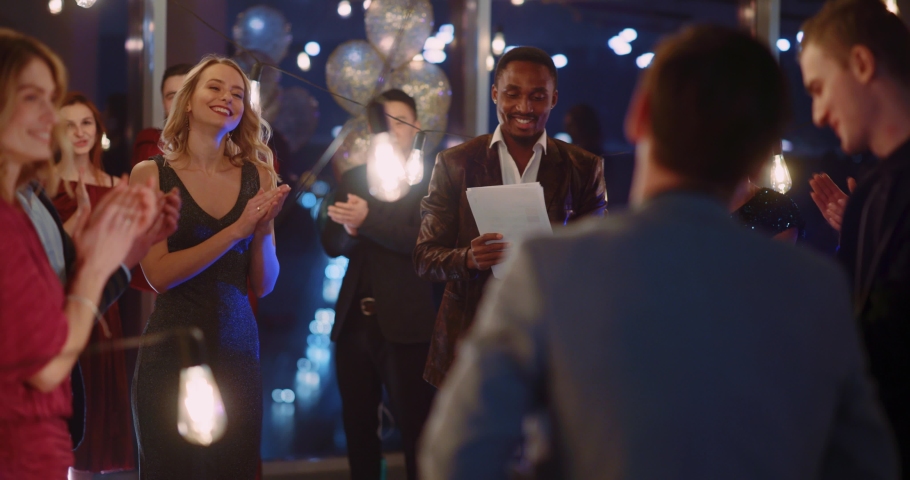 Multi-ethnic people celebrate corporate holiday party. Afro-american young boss leader making speech for his audience. | Shutterstock HD Video #1065924985