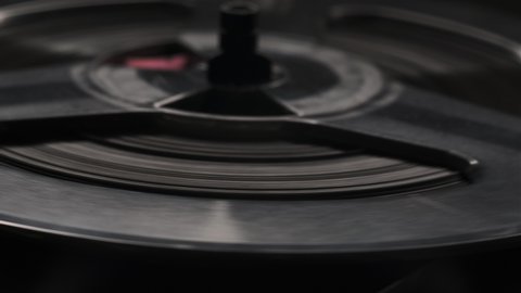 Extreme close up shot of spinning reels on old analogue reel-to-reel audio tape recorder. Dolly spin shot of vintage player. Text LEVEL, MAGNETIC HEAD