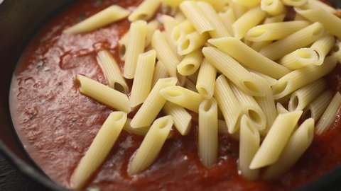 Boiled pasta is poured into the hot tomato sauce with herbs