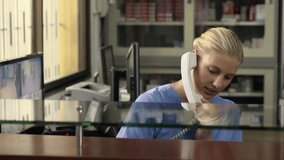 Young woman at work as receptionist and nurse in hospital and talking on the phone with patient for appointment. Health care worker in medical clinic using telephone for information - Powered by Shutterstock - Get 15% off with code: PIKWIZARD15
