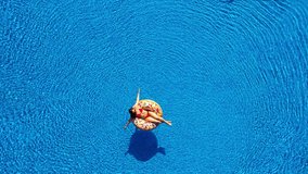 Aerial view of man dives into the the pool while girl is lying on a donut pool float - Powered by Shutterstock - Get 15% off with code: PIKWIZARD15