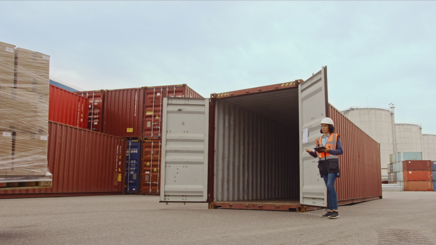 Forklift Driver Loading a Shipping Cargo Container with a Full Pallet with Boxes in Logistics Port Terminal. Latin Female Industrial Supervisor and Safety Inspector with Tablet Managing the Process. Royalty-Free Stock Footage #1065943522