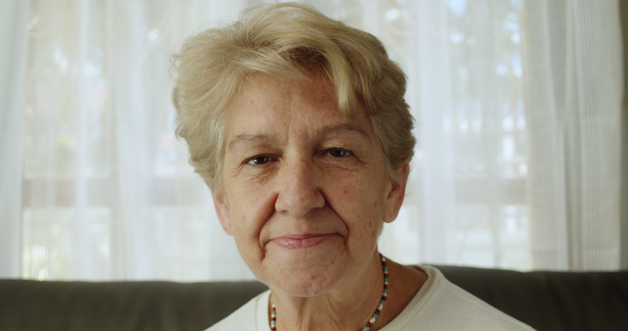 A nice elderly woman after retirement cut short hair with light brown hair smile in a cheerful mood at her home alone.