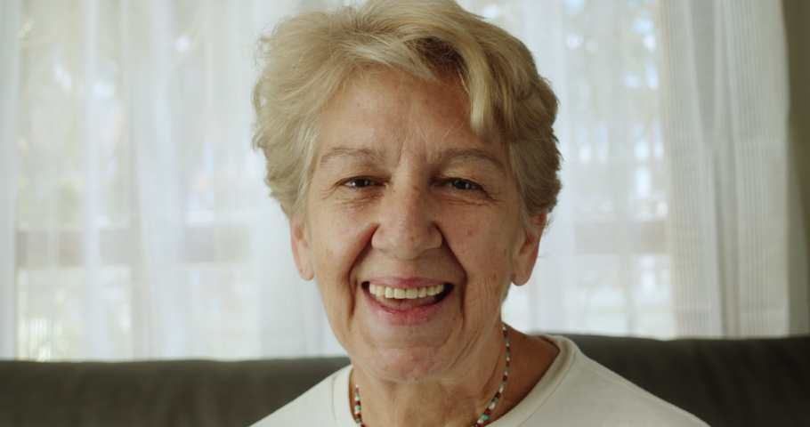 A nice elderly woman after retirement cut short hair with light brown hair smile in a cheerful mood at her home alone.