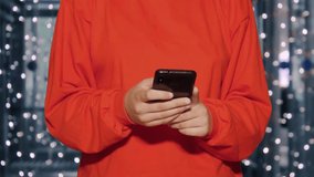 Unrecognizable young woman in red clothes writes text messages on her mobile phone on blurred background - Powered by Shutterstock - Get 15% off with code: PIKWIZARD15