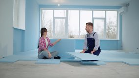 young married couple is engaged in home improvement and renovation and insulates floor with expanded polystyrene before installing laminate indoors