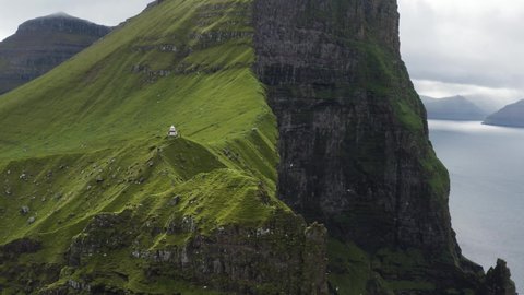 Faroe Islands coast line cliff with birds and lighthouse aerial shot