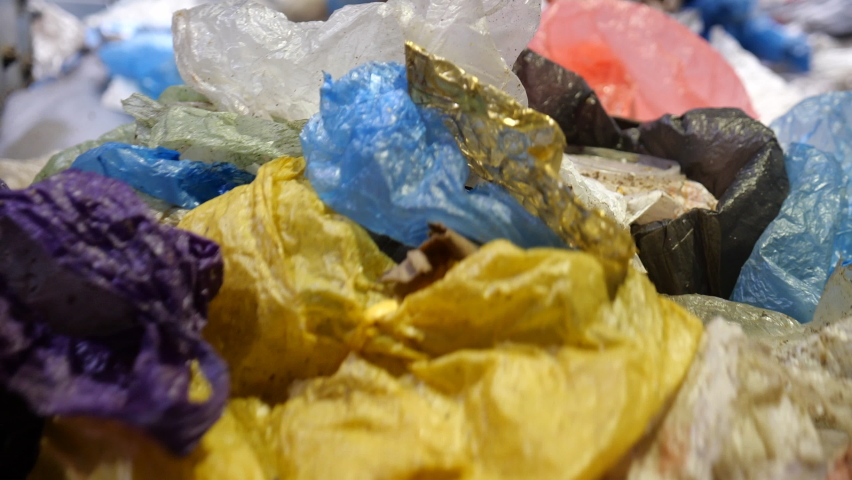 Dirty used plastic bags and trash move on the conveyor belt. Recycling of waste and disposable packaging. Multi-colored plastic waste is sorted for secondary use. | Shutterstock HD Video #1065969181
