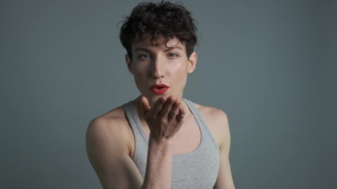 Portrait of handsome transgender man with makeup sending air kiss to camera. Medium shot. Masculine and feminine characteristics in one person. Gender identity concept 4k