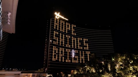 Las Vegas , Nevada , United States - 05 05 2020: Wynn Encore Hotel and Casino With Message During Covid-19 Lockdown. Night View of Building With Police Car in Front