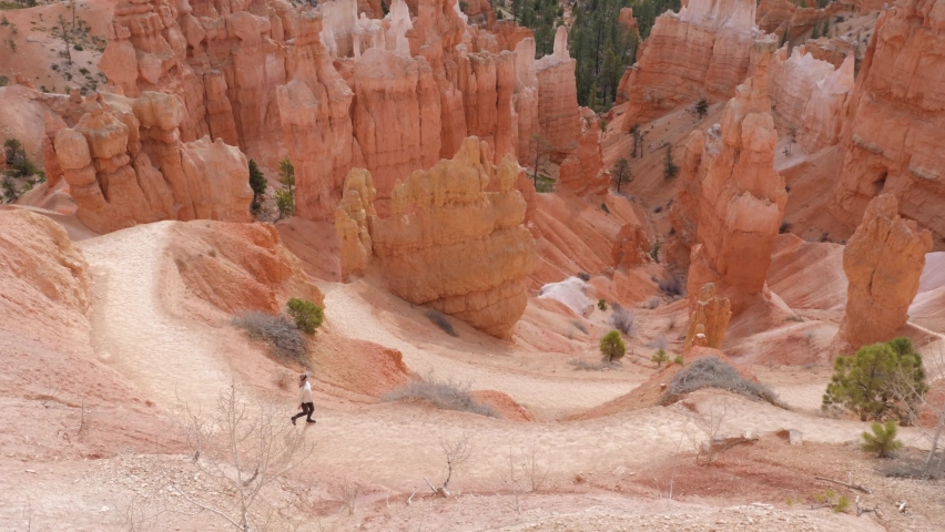 Female hiker walking on trail with hoodoos around in Bryce Canyon National Park in Utah, USA