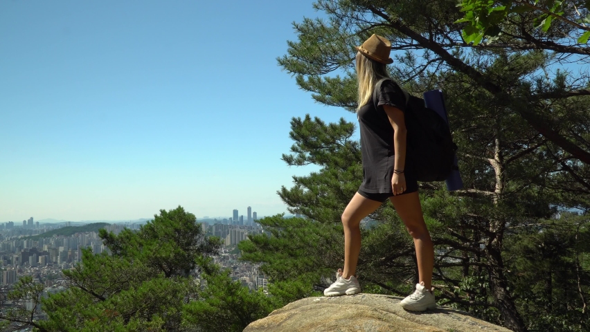 Girl Standing On The Boulders And Looking At The Scenic Downtown Skyline In Seocho-gu District From Gwanaksan Mountain In Seoul, South Korea. - wide shot