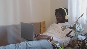 Male african american making a video call with a laptop from on a sofa at home. Work at home.