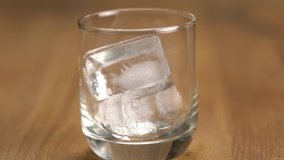 Drop ice cube into a glass on wooden table. Bartender is putting ice cubes into glass for preparing whisky on the rock. - Powered by Shutterstock - Get 15% off with code: PIKWIZARD15