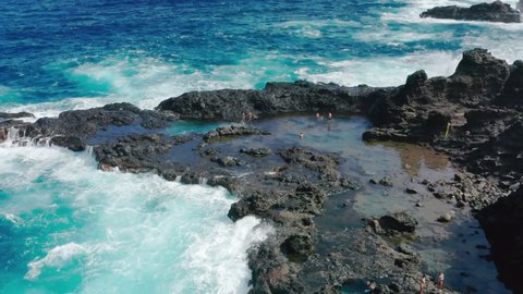 People enjoying pure nature and coast. Aerial 4K people swimming at ocean tide pools. Overhead view of man swimming in natural volcanic pools of blue Pacific ocean on tropical Hawaii island shore USA