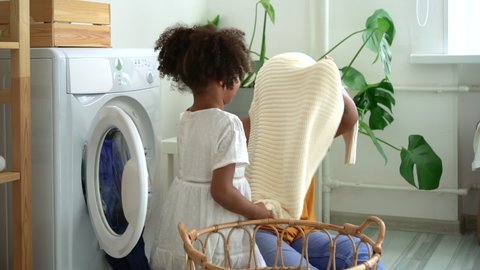 mom and daughter play with clothes have fun and bonding time near washing machine indoors Spbd. smiling african mother and child have happy moment. concept housework, laudry, washer