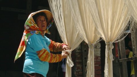 Lanzhou , China - 02 03 2018: Woman checks on noodles drying in the sun.