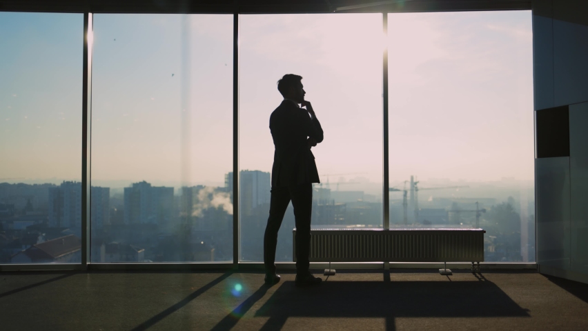 Young Adult Caucasian Entrepreneur Looking into Window Generating New Successful Business Ideas Contemplating Future Staying in Modern Office. Royalty-Free Stock Footage #1065995641