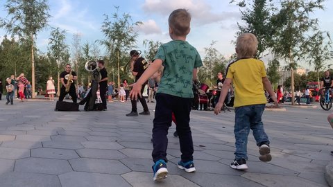 Moscow, Russia - August 14 2019: Two young boys dancing in Zaryadye park next to street musicians. Concert at the park next to red square 