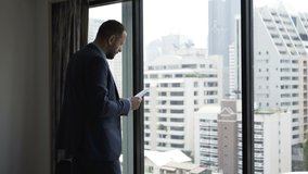 Young businessman reading, analyzing documents standing by window at hotel - Powered by Shutterstock - Get 15% off with code: PIKWIZARD15