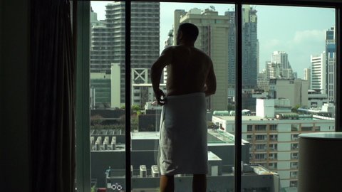 Man after shower wearing towel by window at home, super slow motion