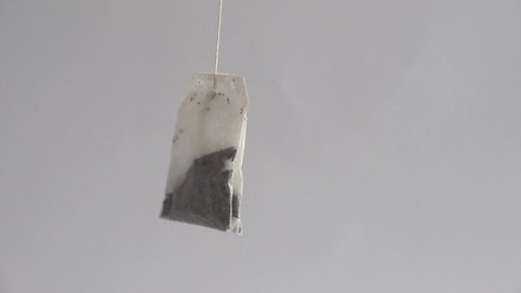 A tea bag is whirling on a label string around its axis. A clip about wasting, consuming, recycling, renewing, shifting, disposing, littering, sorting, assorting, polluting, nonsense, mind emptiness