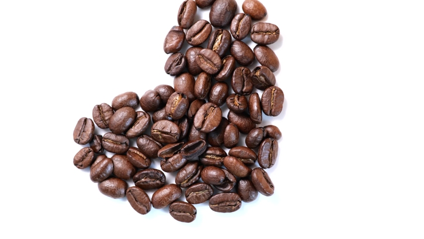 Closeup high angle view of rotating coffee beans in heart shape on white background.