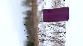 Vertical video small thermos with steaming hot drink on snowy winter background.