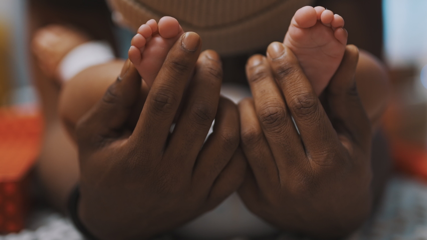 Black father playing with baby feet. Close up slow motion. High quality 4k footage Royalty-Free Stock Footage #1066010002