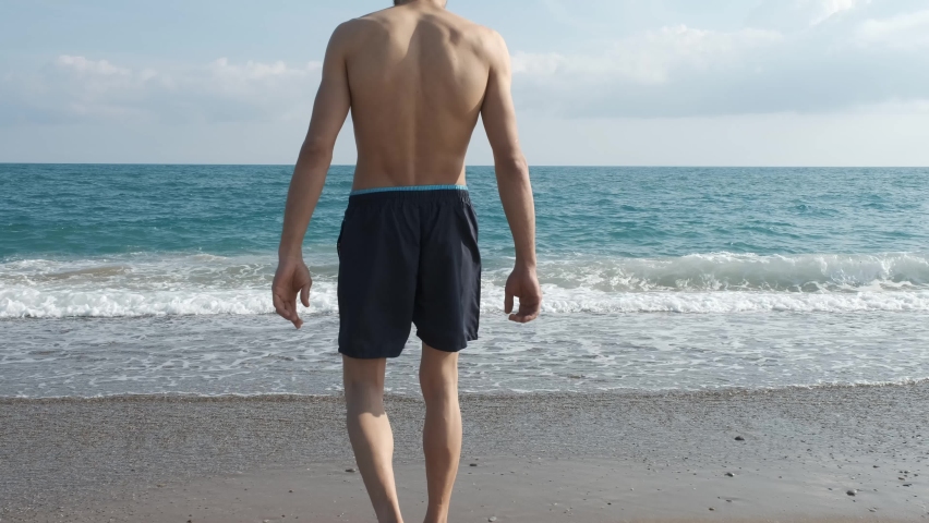 The man preparing to swim is walking towards the sea.