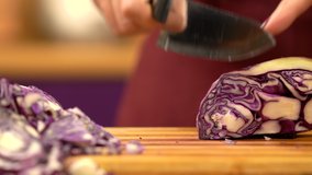 Woman's hand cutting 
red cabbage, close view. Female's hand slicing red cabbage in kitchen. Preparing Vegetable for salad. High quality 4k video.