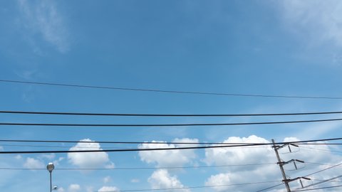 blue sky and electricity wire. clouds moved horizontal throughout power line. bright sun shine in a midday in summer sunny day. clean energy from sunlight, solar reusable energy in a city.