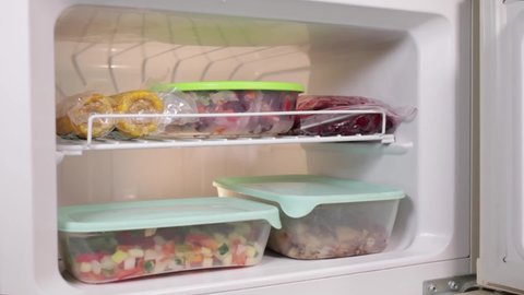 The fridge door opens, frozen vegetables and fruits, soup preparations, vegetable mixtures, corn in a vacuum in the freezer. Cold semi-finished products for frying and baking.