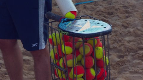 Brasilia , Brazil - 10 01 2020: Brasilia, Brazil - October 2020: Man using a tube full of beach tennis balls to fill a practice basket
