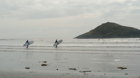Tofino , Canada - 09 19 2020: Two surfers wading out into ocean in Tofino
