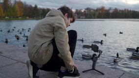 Vlogger boy with mobile phone camera stabilizer recording outdoor video blog in autumn park. Teenager shooting video for travel vlogging. Catherine Park, Tsarskoye Selo, Saint Petersburg, Russia.